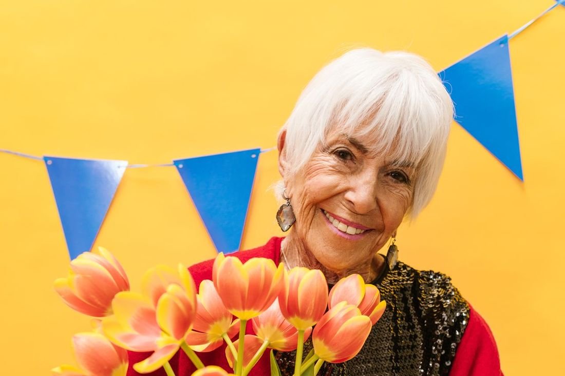 Smiling woman in her late 60s holding a bouquet of tulips during a relaxing screen-free afternoon